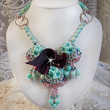Collier Blue Flowers brod&eacute; avec un ruban de soie framboise/truffe &agrave; laquelle s&rsquo;ajoute : cabochons, perles nacr&eacute;es Rosaline et Ivoire, toupies Jet, anneaux ovales, perles marbr&eacute;es Bleu Ciel et Blanc